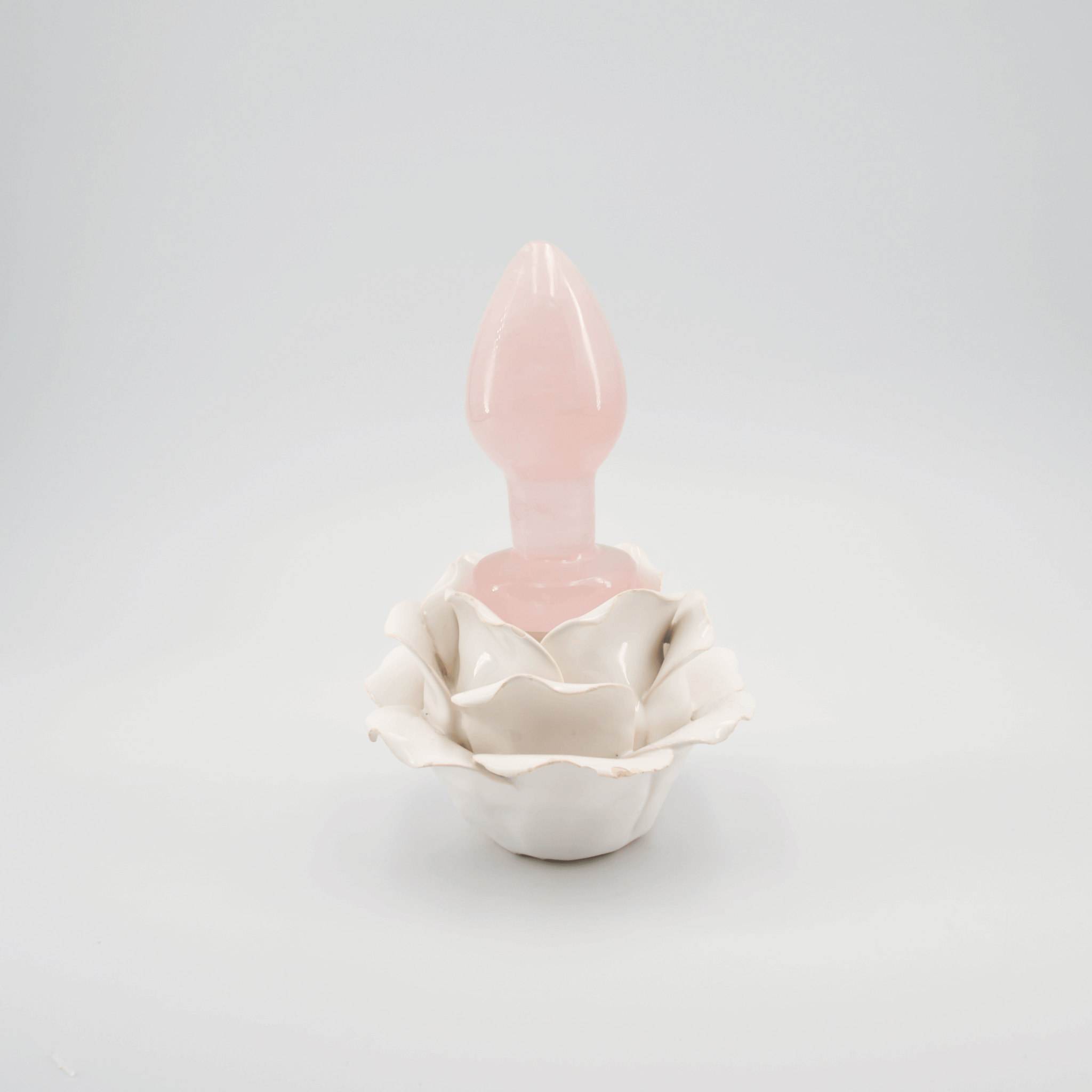 Rose quartz crystal wand nestled in a ceramic rose holder, symbolizing self-care and wellness.