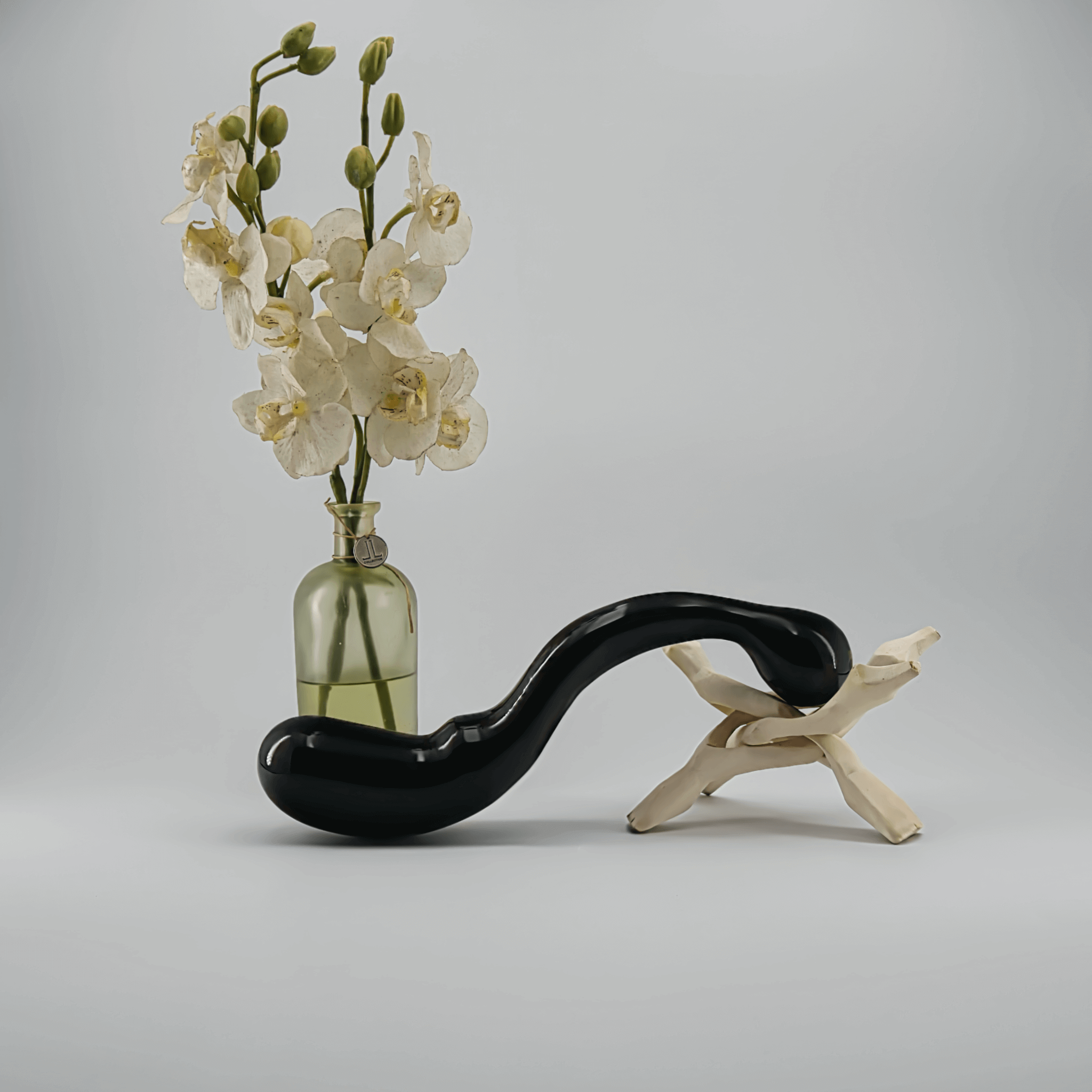 A sleek black vase with white orchids, elegantly displayed next to a minimalist stand.