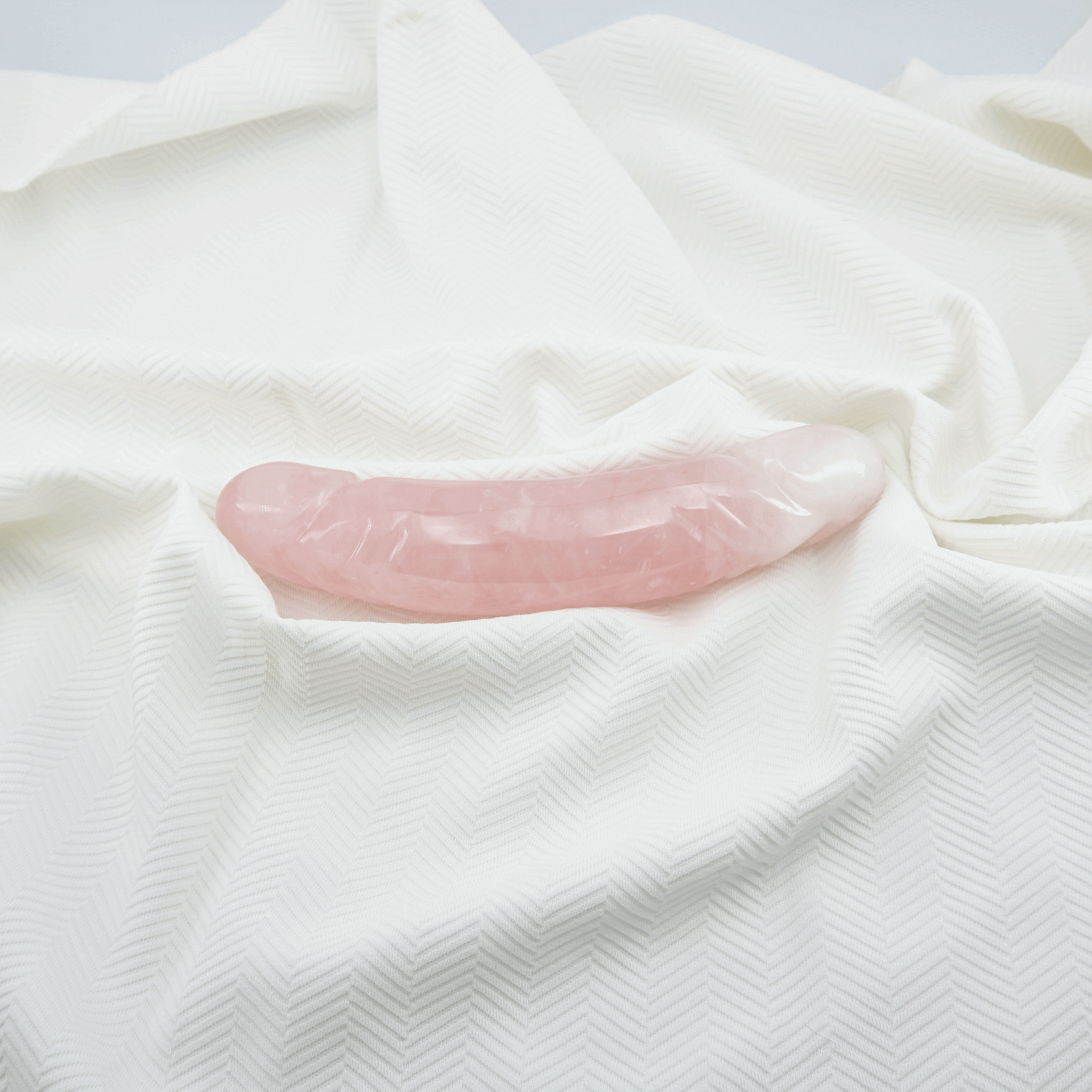 Rose quartz pleasure wand resting on a soft white fabric, symbolizing mindfulness and intimacy.