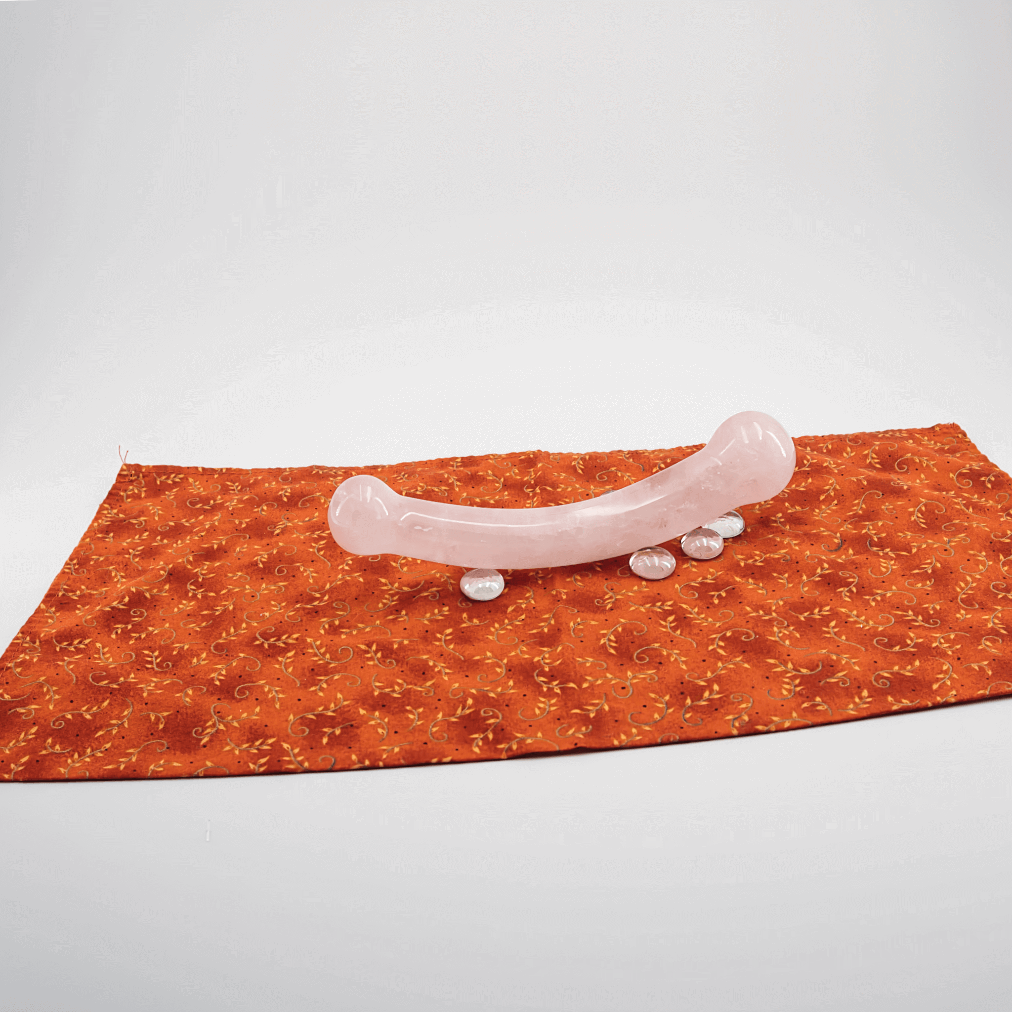 Crystal wand on an orange fabric, showcasing its smooth design for self-care routines.