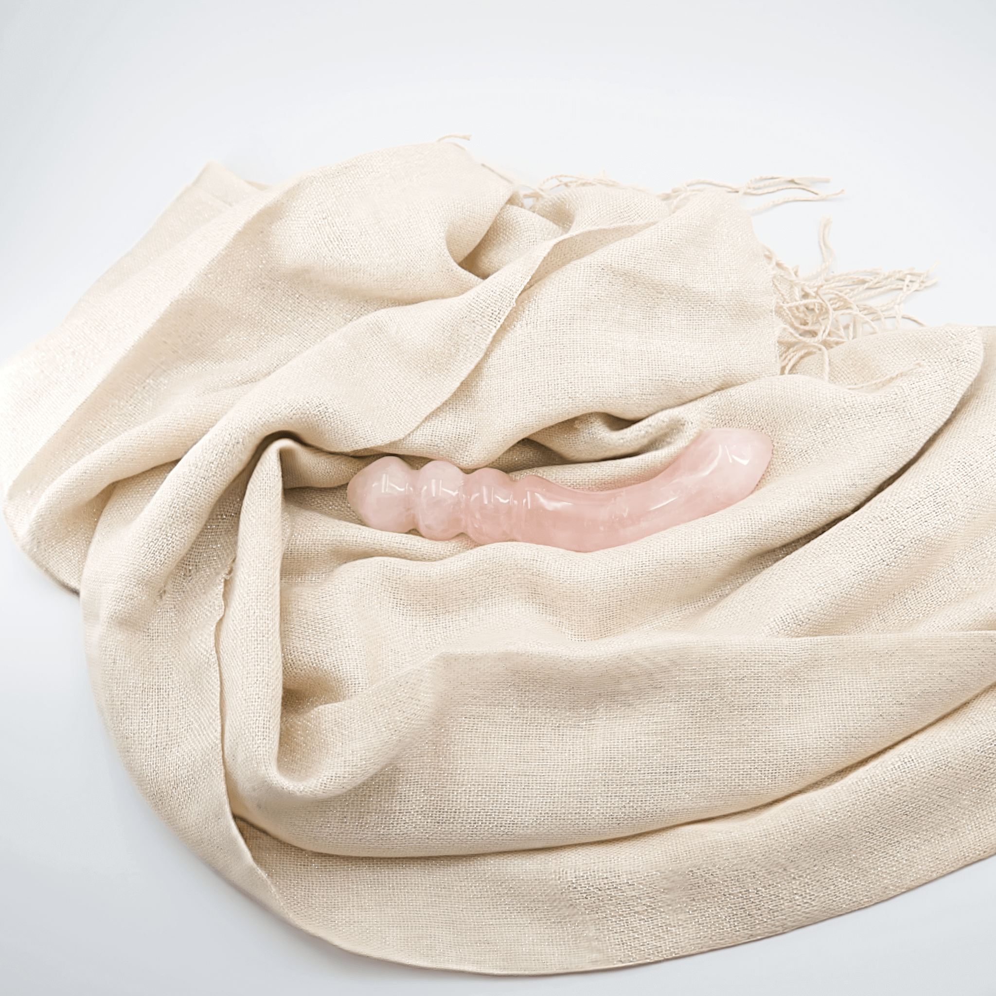 Crystal dildo resting on a soft, beige cloth, showcasing its smooth design and inviting texture.